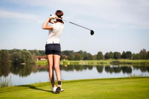 Woman golfing in mid-swing
